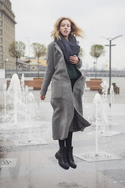 Beautiful blonde young caucasian woman in grey coat and scarf wa — Stock Photo, Image