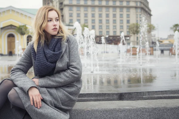 Bella bionda giovane donna caucasica in cappotto grigio e sciarpa wa — Foto Stock