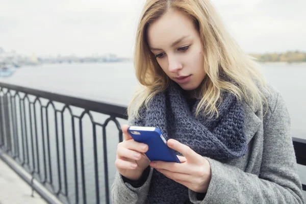 Belle femme blonde sur une promenade dans la ville européenne en utilisant son smar — Photo