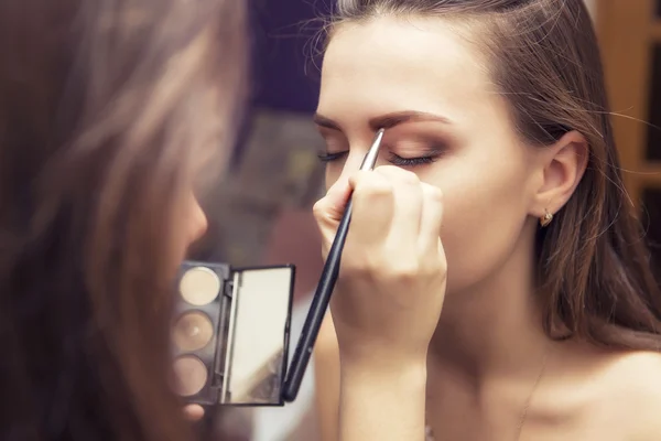 Brunette make-up artiest vrouw toepassing maken omhoog voor een brunette br — Stockfoto