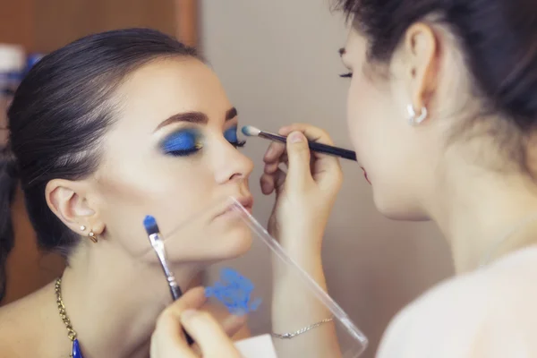 Morena compõem artista mulher aplicando maquiagem para uma morena mo — Fotografia de Stock
