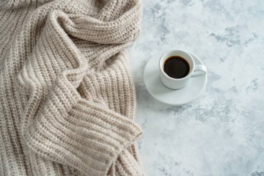 Masanın üzerinde örülmüş bir kazak ve bir kupa kahve var.