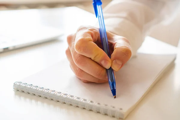 female hand makes notes with a pen in a notebook