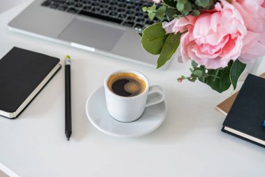 Masanın üzerinde bir laptop, yanında bir kupa kahve ve bir günlük var.