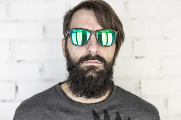 Hippi. Yeşil güneş gözlüklü genç sakallı bir adam portresi
