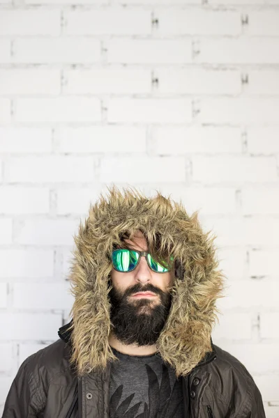 Portrait d'un jeune homme barbu avec des lunettes de soleil vertes et fourrure ho — Photo