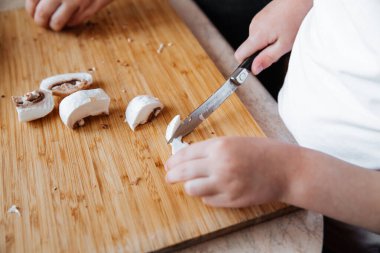 Tahtada taze şampiyon mantarları. Bir kız ve annesi bıçakla mantar kesiyor. Birlikte geçirdiğimiz zaman. Aile kavramı