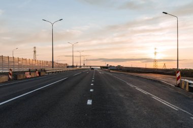 Günbatımının arka planına karşı ses geçirmez panelleri olan yeni inşa edilmiş yol.