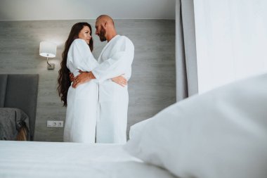 Birbirine aşık bir çift, beyaz elbiseler giymiş, şefkatle birbirlerine bakıyorlar.