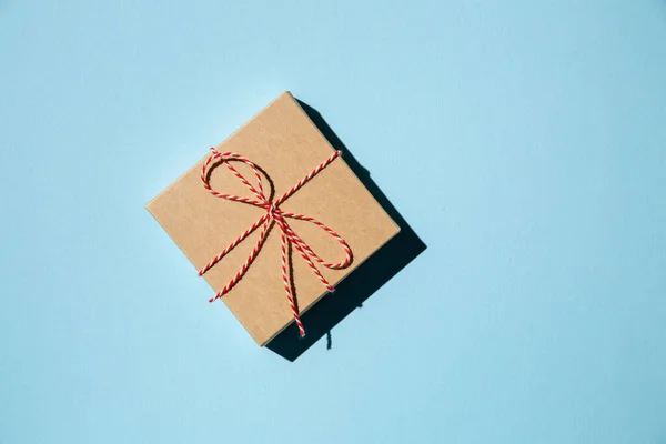 Scatola regalo o regalo avvolto in carta artigianale su sfondo blu. Regalo vacanza. — Foto Stock