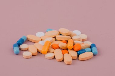Pembe arka planda çeşitli ilaç hapları, haplar ve kapsüller. Bir sürü renkli hap..
