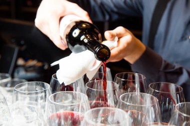 Garson bardaklara kırmızı şarap doldurur. Partide şarap..