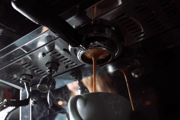 Preparation of espresso. Coffee pours from the coffee machine into the Cup. Professional coffee brewing.