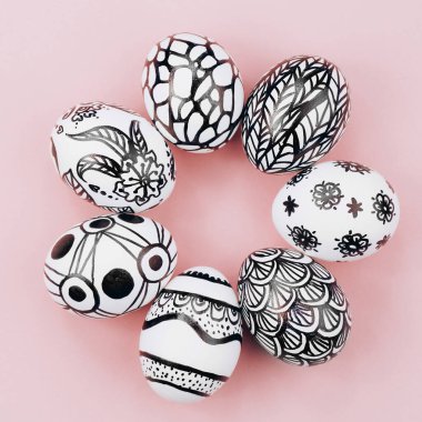 Paskalya yumurtaları siyah ve beyaza boyanır, soyutlanır, daire şeklinde dizilir. Pembe arka planda boyanmış Paskalya yumurtaları. Düz yatıyordu. Kapat. .