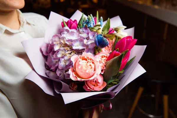 Das Mädchen hält einen prachtvollen Strauß mit bunten Blumen in der Hand — Stockfoto