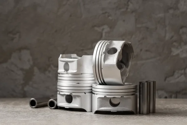 Um conjunto de novos pistões para reparar freios de carro em um fundo de concreto cinza, espaço de cópia — Fotografia de Stock