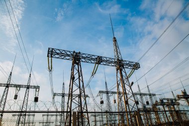 Elektrik direkleri ve yüksek voltajlı elektrik hatları dikenli tellerin arkasında.