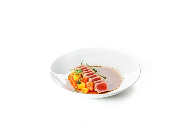 Cooked juicy tuna steak with vegetables on a white stone plate. Restaurant food. Seafood. Isolated — Stock Photo, Image
