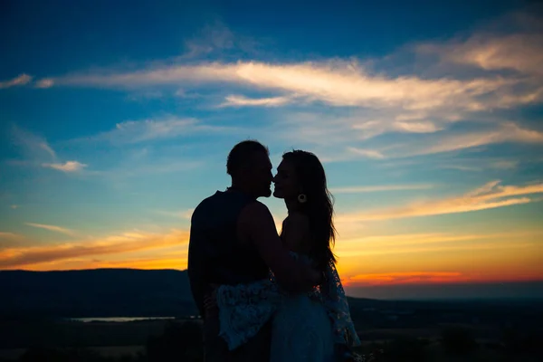 夕阳西下，在高山和大海的背景下，一对恋人拥抱和亲吻的轮廓 — 图库照片