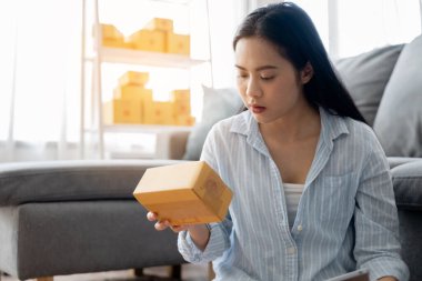 Küçük işletme sahibi Asyalı kadın çevrimiçi sipariş için müşteriye göndermek üzere ürün hazırlıyor.