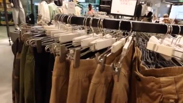 Centro comercial. Hay un montón de pantalones colgando de una percha en la tienda. La cámara se mueve a lo largo de todo el rack. — Vídeo de stock