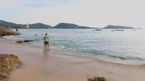 Tropical beach in Phuket where people walk and swim. Boats float on the water — Stock Video