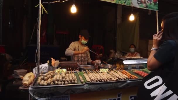Närmatsmarknaden i Bangkok. En försäljare som bär en skyddande medicinsk mask säljer lokal mat. Livet i Thailand under coronavirus, covid 19 — Stockvideo