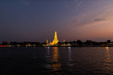 Gün batımında Chao Phraya nehrinden Aydınlanmış Wat Arun Tapınağı manzarası. Bangkok 'taki Budist tapınağı