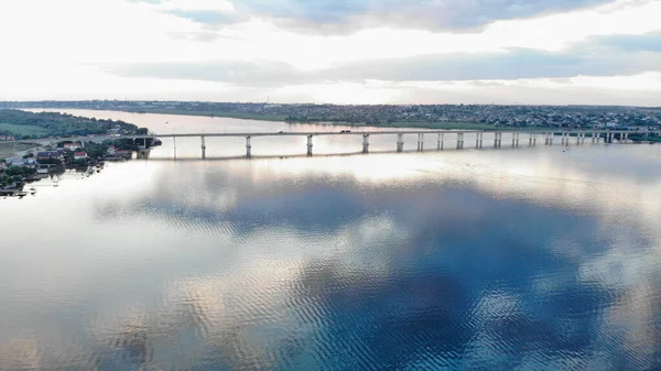 Автомобільний міст через річку Дніпро. На одному березі річки є місто, а на іншому - літні котеджі. — стокове фото