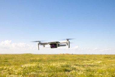 Yeşil alanda kameralı uçan beyaz dron.