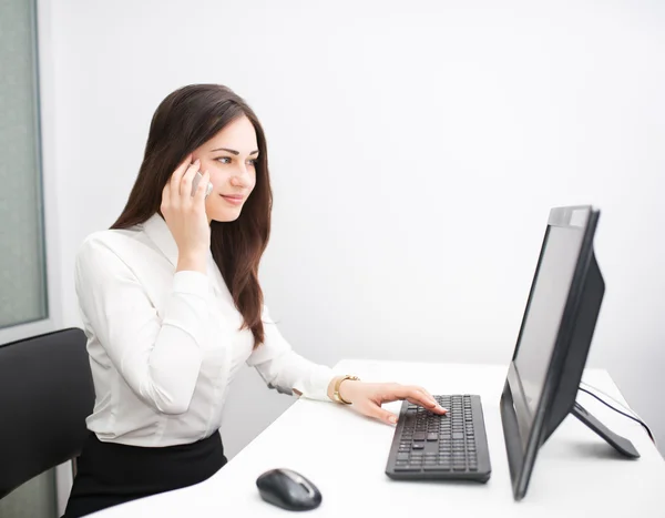 Mujer de negocios habla por teléfono mientras está sentada en la computadora —  Fotos de Stock