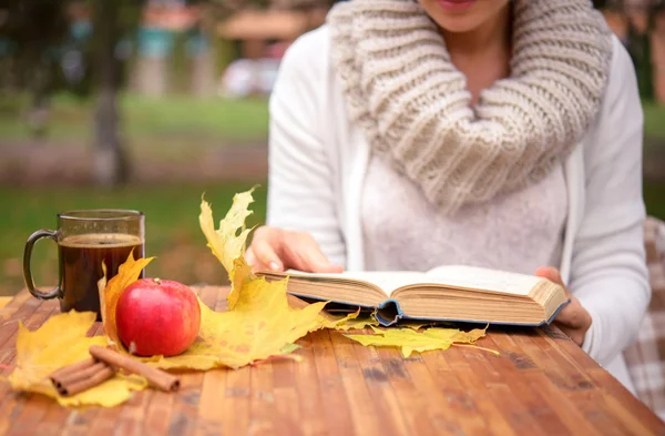 Dívka čtoucí knihu u stolu s podzimní listí Royalty Free Stock Obrázky