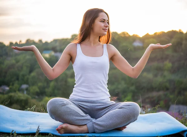 Krásná dívka meditovat při západu slunce zasedání šíření zbraní Stock Snímky