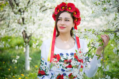 smiling girl in national dress holding a blossoming branch