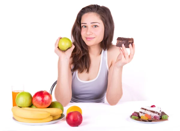 Девушка выбирает между яблоком и тортом — стоковое фото