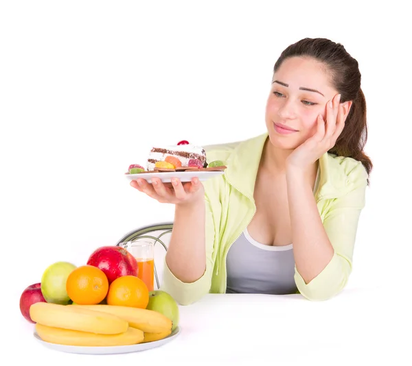 Девушка выбирает между фруктами и сладостями — стоковое фото