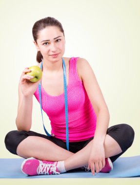 girl sitting on a mat and holding an apple