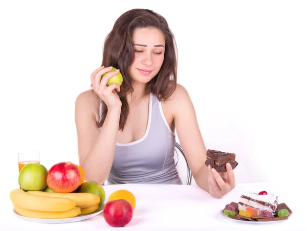 Mädchen wählt zwischen einem Apfel und einem Kuchen — Stockfoto