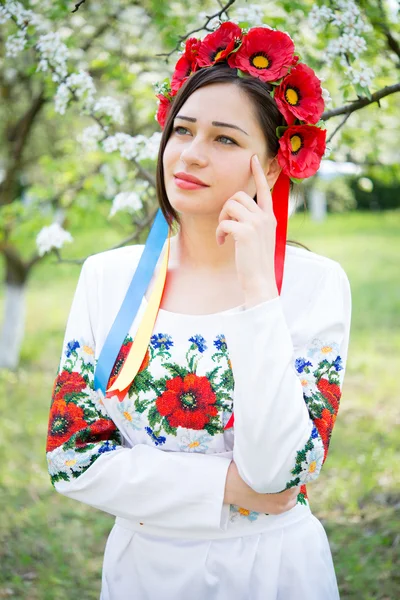Chica reflexiva en ropa nacional en el jardín floreciente — Foto de Stock