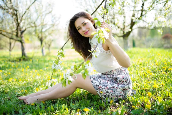 Красива дівчина сидить під квітучими деревами — стокове фото