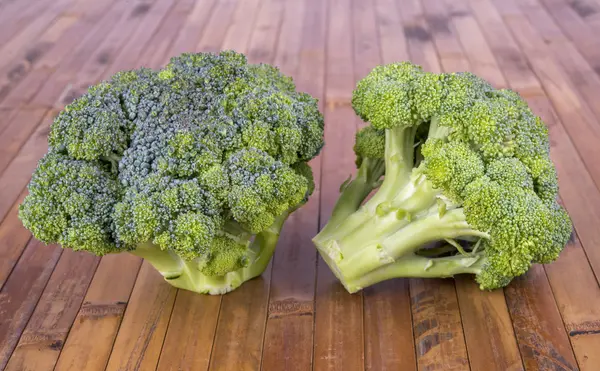 Two fresh broccoli on a wooden surface — ストック写真