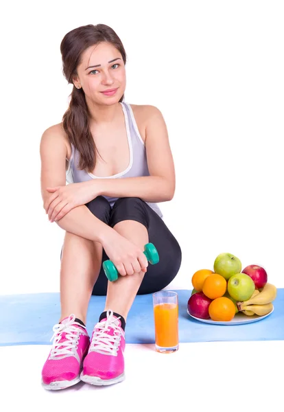 Girl on the carpet with dumbbell and fruit Stock Photo