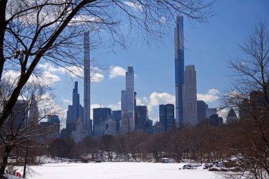 New York 'taki Central Park' ın karlı gölünün arkasındaki milyarder sırasının yüksek gökdelenleri.
