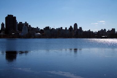 New York 'un yukarı doğu yakasında Manhattan' daki Central Park 'taki ikonik rezervuarın arkasında.