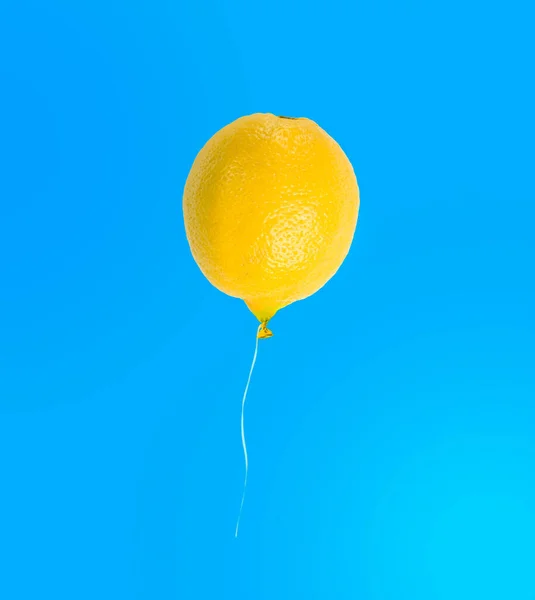 Mavi arka planda izole edilmiş limon balonu, komik tropikal meyve kavramı