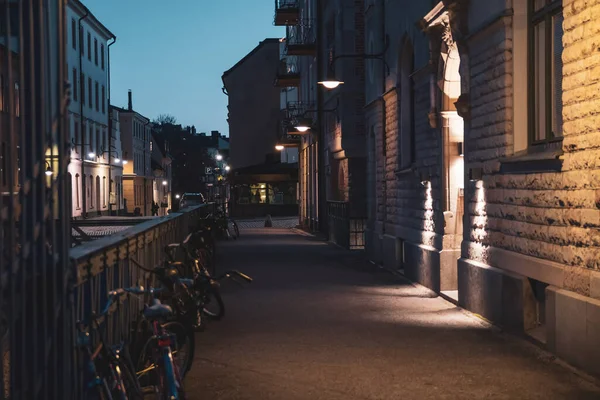 Stockholm 'deki akşam caddesinin manzarası. Bisikletler çit boyunca park edilmiş..