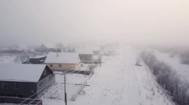 Kuzeydeki bir köyde şiddetli kar yağışı, karda küçük ahşap evler, yoğun sis. Hava görüntüsü, İHA 'dan çekim..