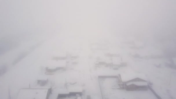 遠く北の村で厳しい雪の冬には、雪の中で小さな木造住宅、重い霧。空中からの眺めドローンからの撮影. — ストック動画