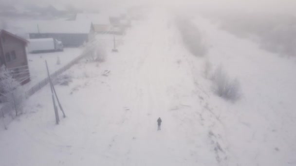 寒冷的冬天，在遥远的北方的一个村子里，小木屋在雪地里，浓雾弥漫。空中观察，无人驾驶飞机射击. — 图库视频影像