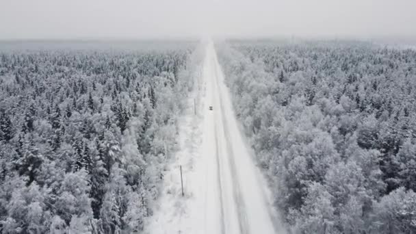 Αεροφωτογραφία κορυφή από drone, πουλιά άποψη μάτι του χειμερινού τοπίου και χιονισμένο δρόμο πάγου, αυτοκίνητο κινείται στην περιοχή που περιβάλλεται από όμορφο κωνοφόρο δάσος 4k — Αρχείο Βίντεο